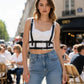 Adjustable cage chest harness with black faux-leather shoulder straps over a white crop top on a street-style model