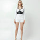 Black caged-strap overbust corset bustier in vegan leather, worn over a white top.