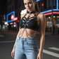 HarnessClub black chain-detail leather body harness worn over a black top with light-wash jeans.
