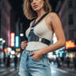Black studded vegan-leather chest harness worn over a white ribbed tank top