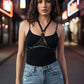 Black studded vegan leather halter triangle chest harness by HarnessClub worn by a model in a city at night