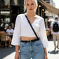 Black thin crossbody strap harness belt by HarnessClub, vegan leather accessory worn over a white top.