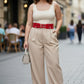 Red double-buckle leather belt for plus-size women worn over beige outfit