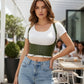 Khaki vegan-leather underbust corset belt with lace-up front and straps, worn over a white top.