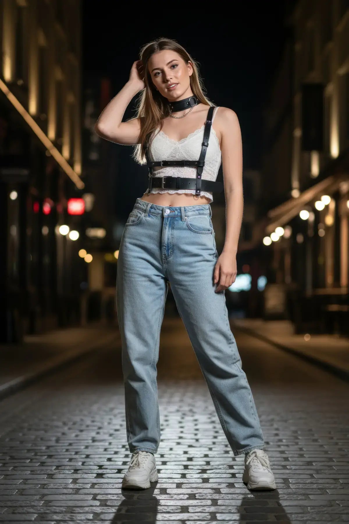 Siyah kadın vücut harnessı bel ve göğüs çevresinde kayışlı, beyaz dantel crop bluzla açık mavi jean üzerinde sokak stilinde