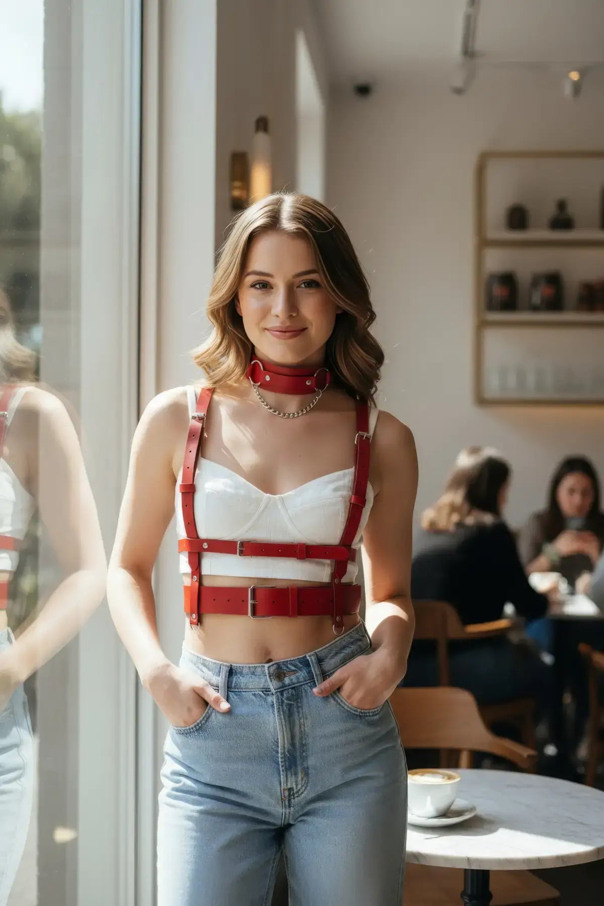 Kırmızı deri vücut aksesuarı tokalı yelek, model üzerinde beyaz crop üst ve mavi kot pantolon.