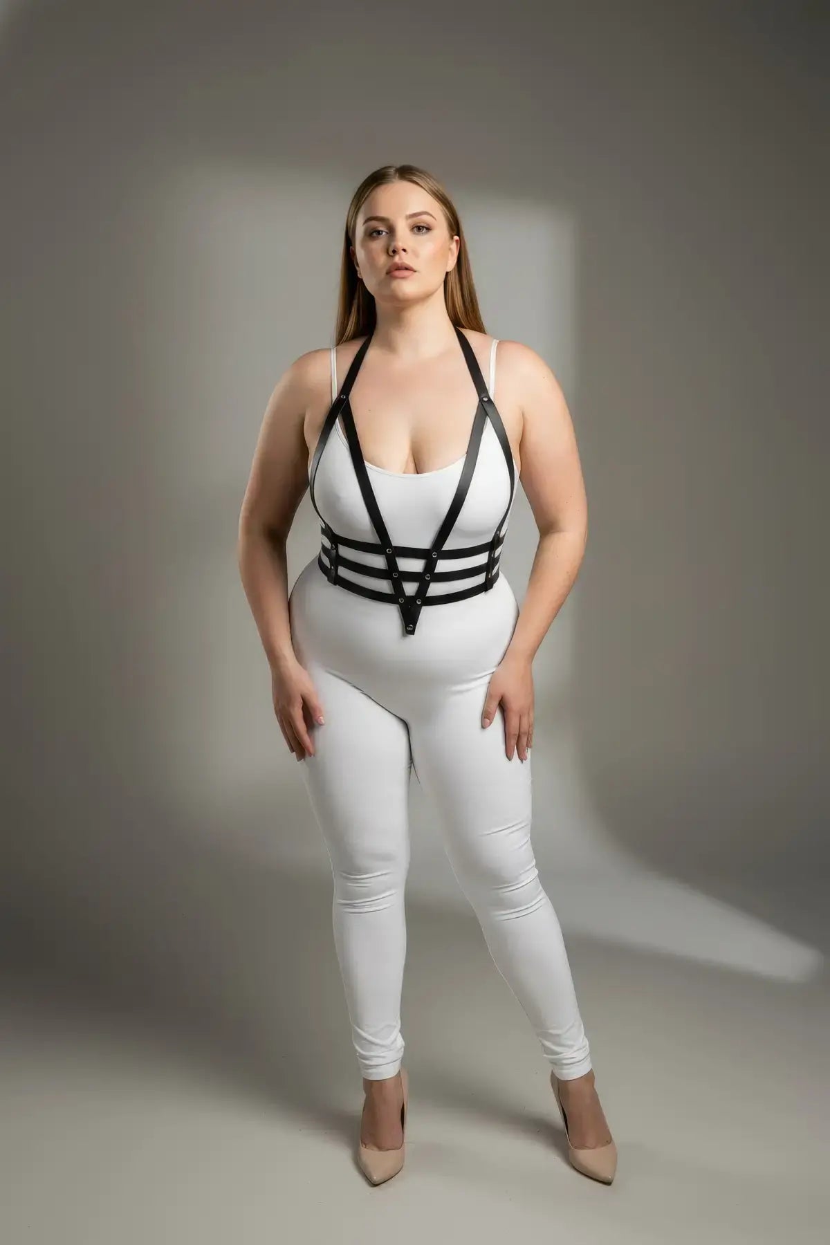 Plus size black adjustable faux leather body harness worn over a white bodysuit