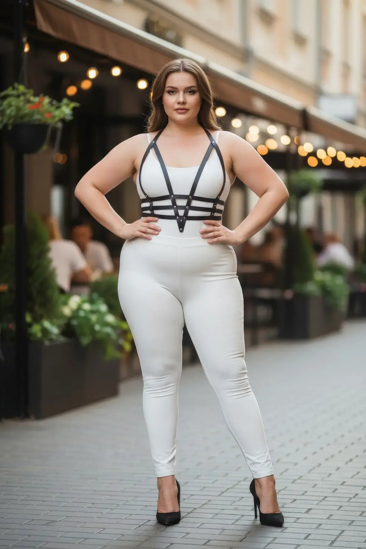 Plus-size black adjustable faux-leather body harness on a model wearing white bodysuit; HarnessClub.