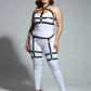 Plus-size black faux-leather garter harness set with adjustable straps by HarnessClub, worn over a white bodysuit