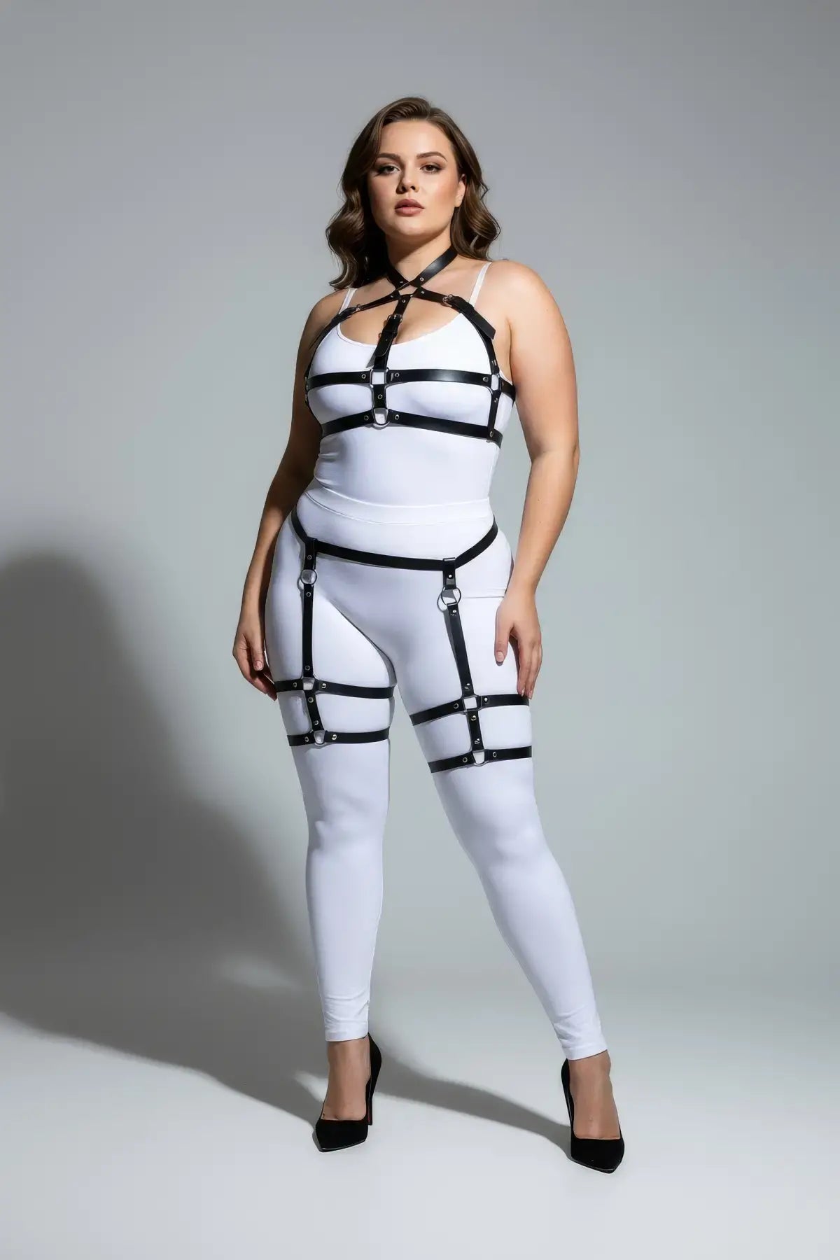 Plus-size black faux-leather garter harness set with adjustable straps by HarnessClub, worn over a white bodysuit