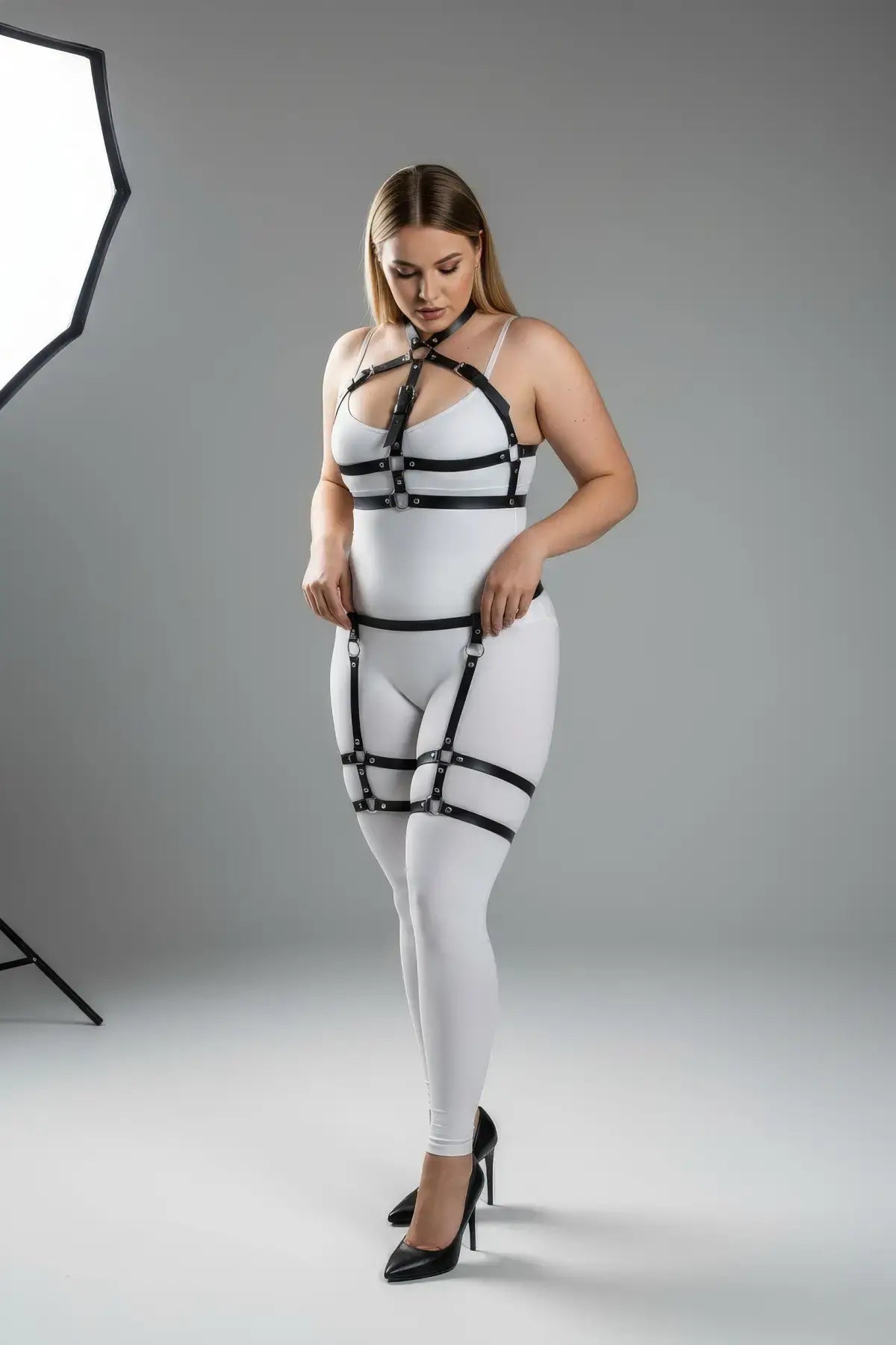 Plus size black adjustable garter harness set by HarnessClub, faux leather body accessory worn over a white bodysuit.