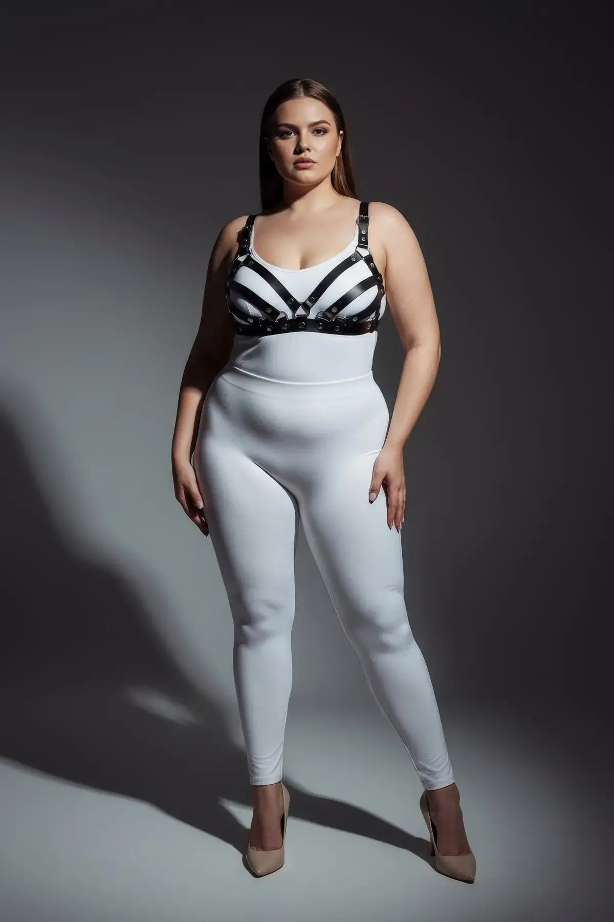 Plus-size black faux-leather bra harness with adjustable straps, worn over a white top.