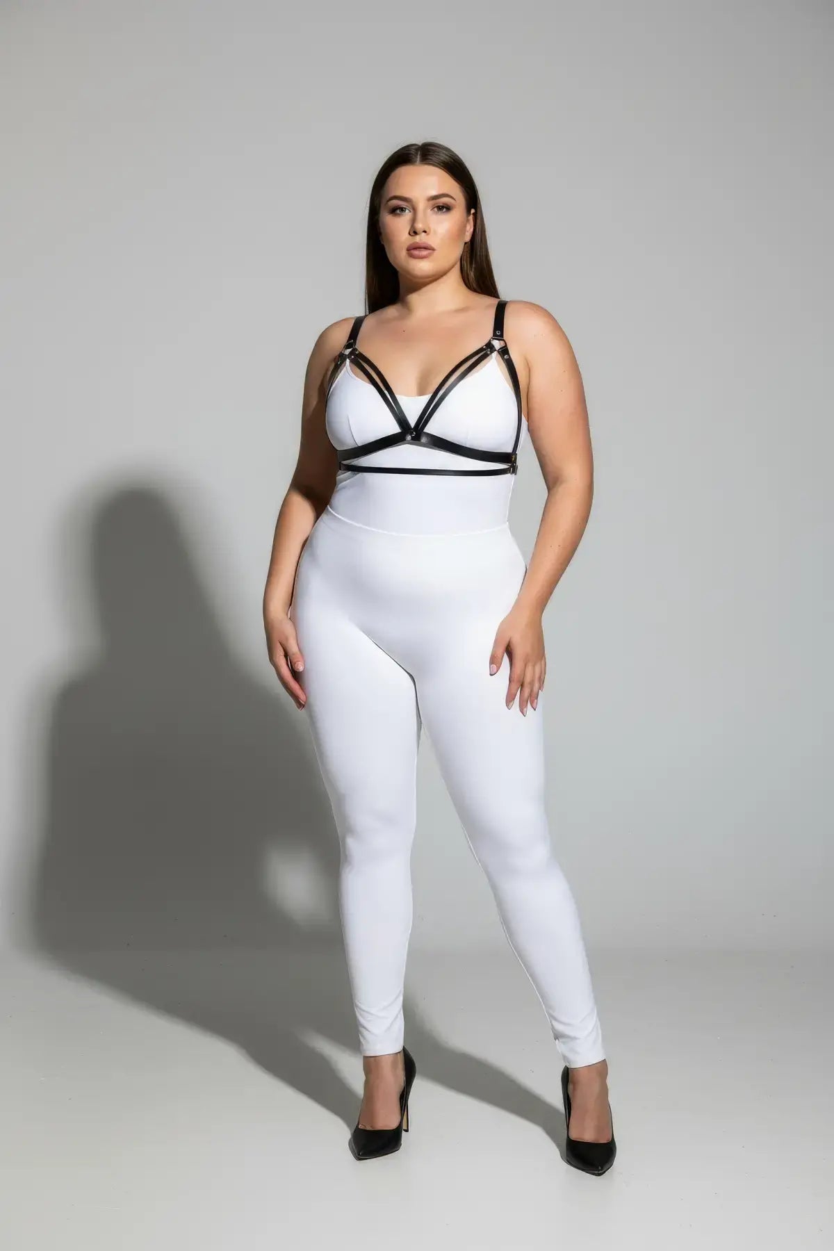 Plus-size black faux leather bustier-style harness over a white bodysuit with bold strap details