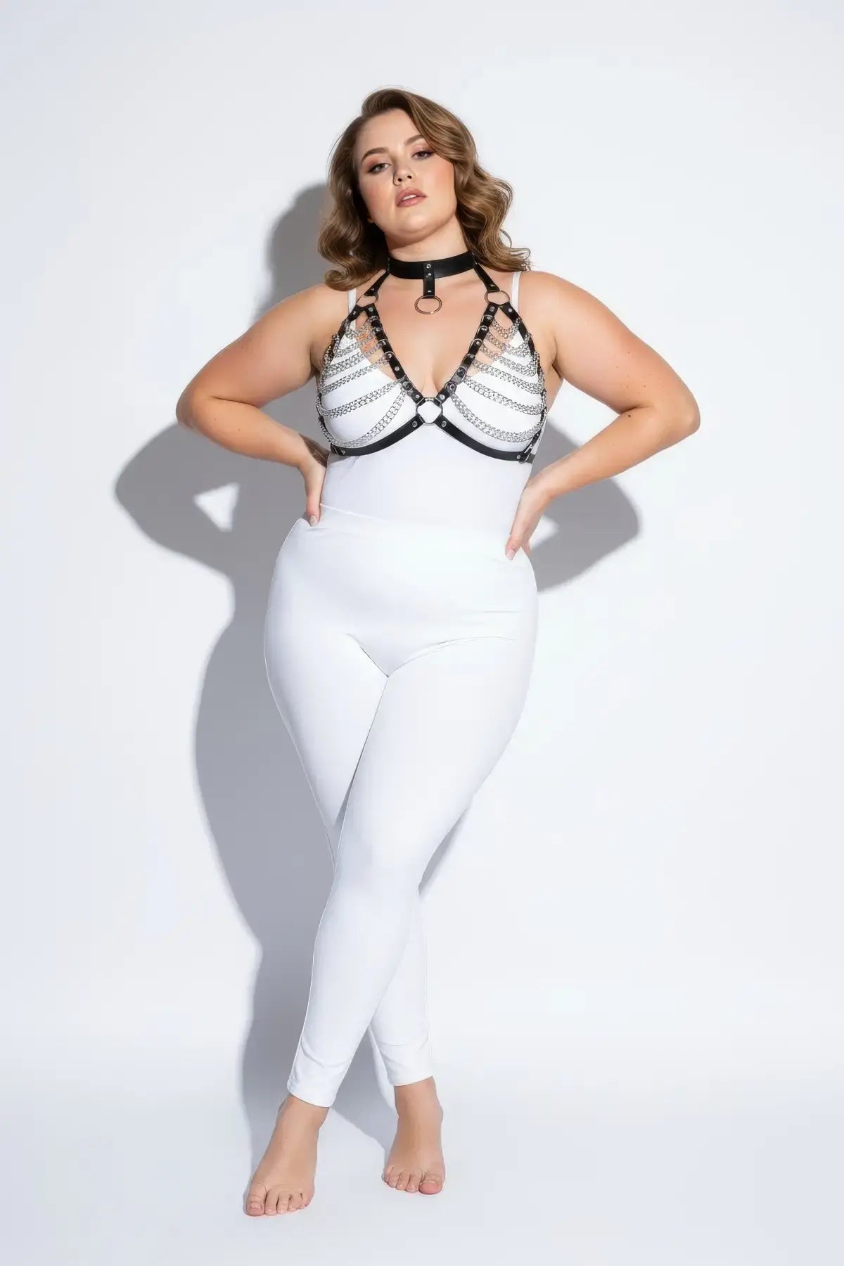 Plus-size black faux-leather chain-and-collar body harness with silver rings worn by model.