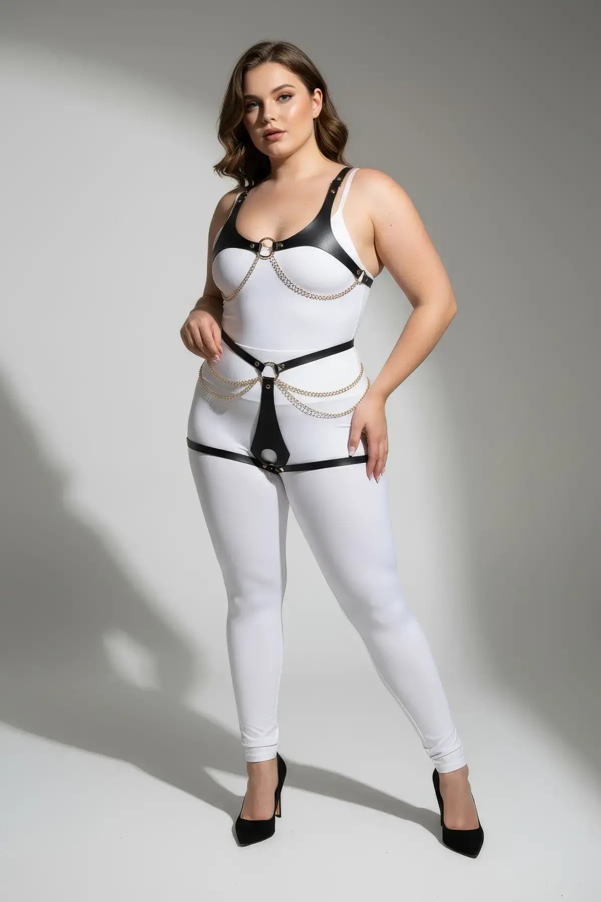 Plus-size black faux-leather body harness with O-ring and gold chains worn over white bodysuit