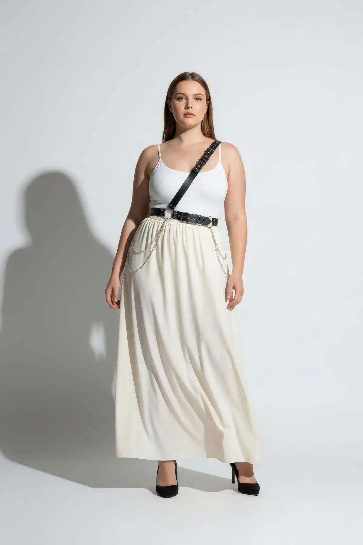 Plus-size black chain-detail body harness belt with silver chains worn over a white tank top and cream skirt