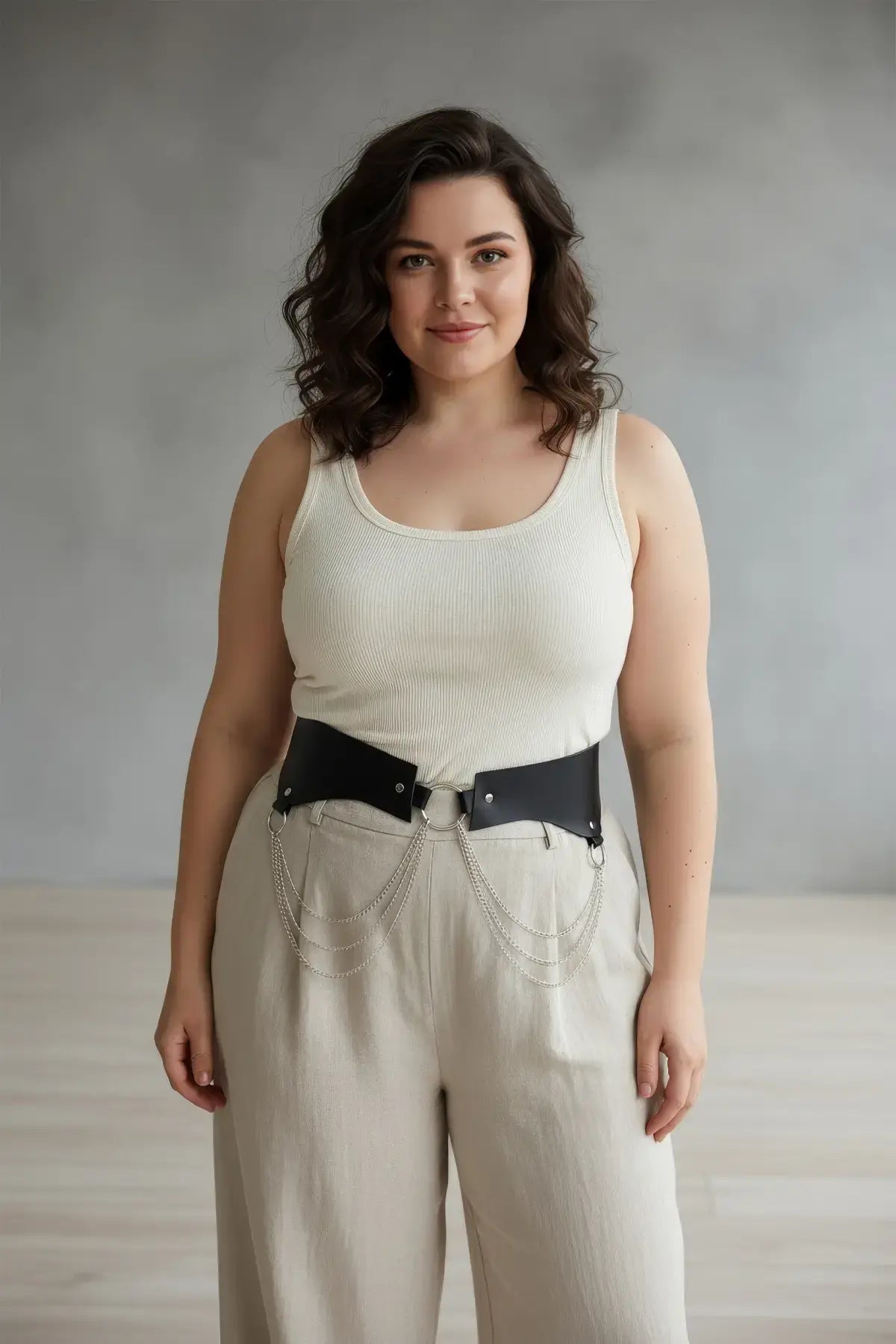 Plus-size black vegan-leather chain-detail corset harness worn at the waist.