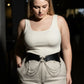 Plus-size black chain-detail corset harness worn over a white ribbed tank and beige pants with chain drapes