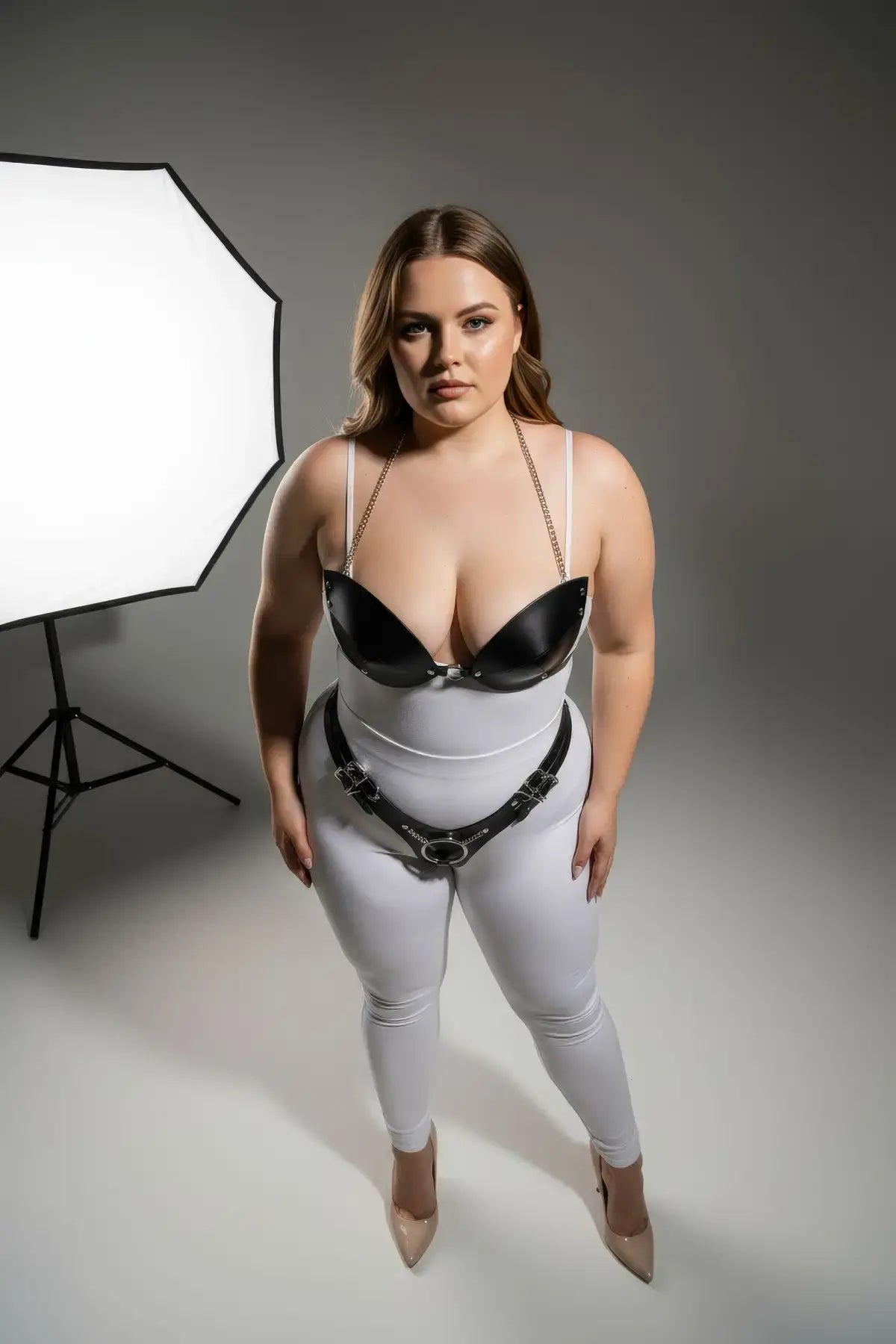 Plus-size black chain-detail faux leather harness set by HarnessClub worn over pants; metal chain straps and waist belt