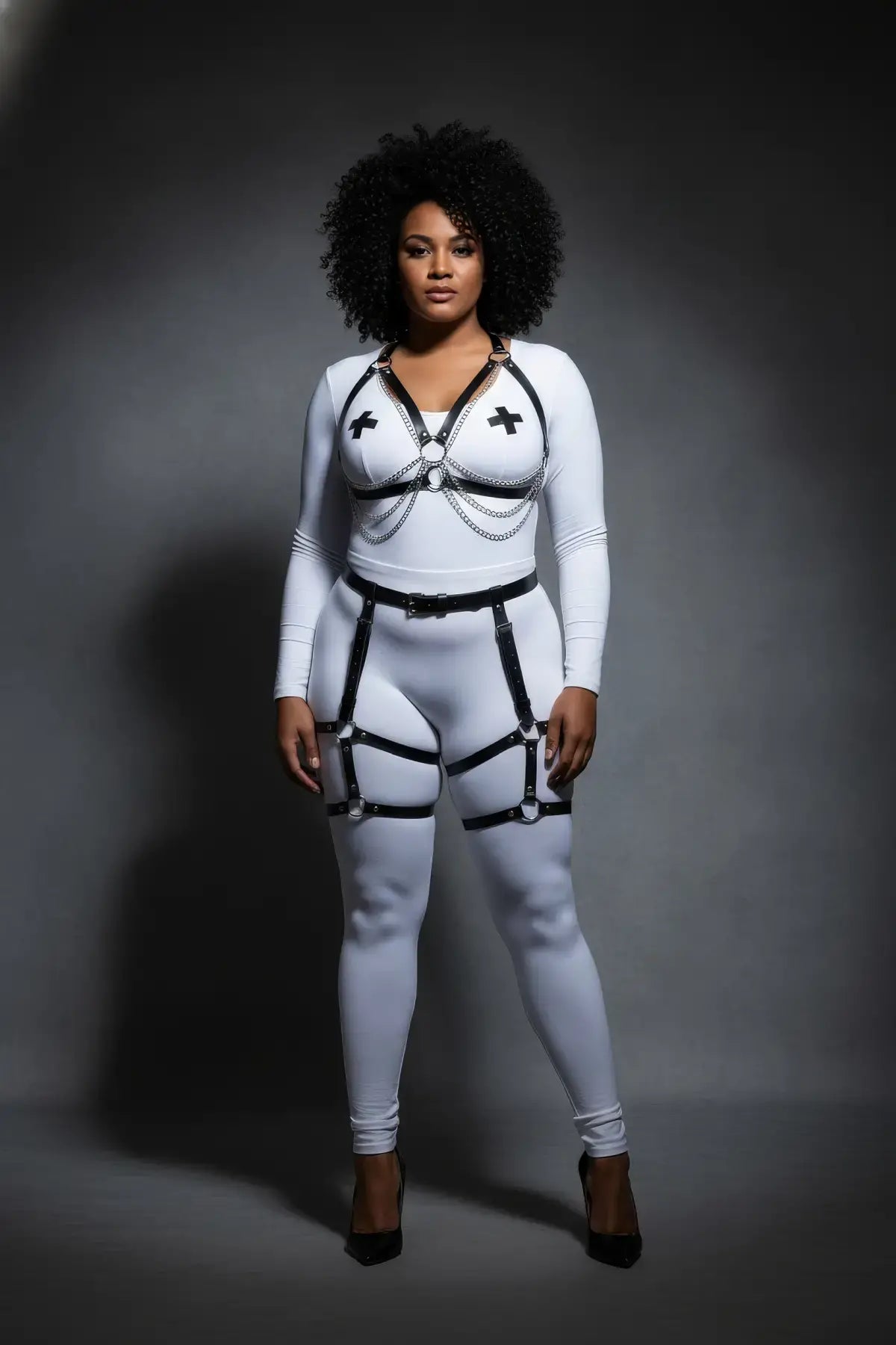 Plus-size black chain-drape thigh-cage harness set on model over white bodysuit; vegan leather with silver chains.