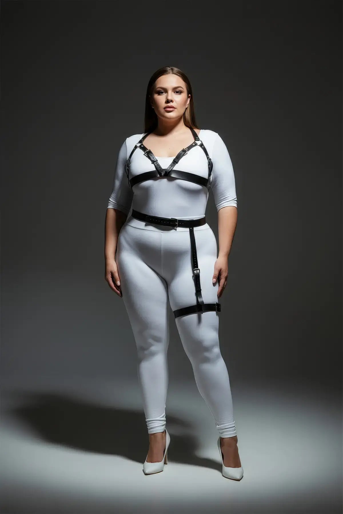 Plus-size black chest harness and single-leg garter set in vegan leather worn over a white bodysuit by HarnessClub.