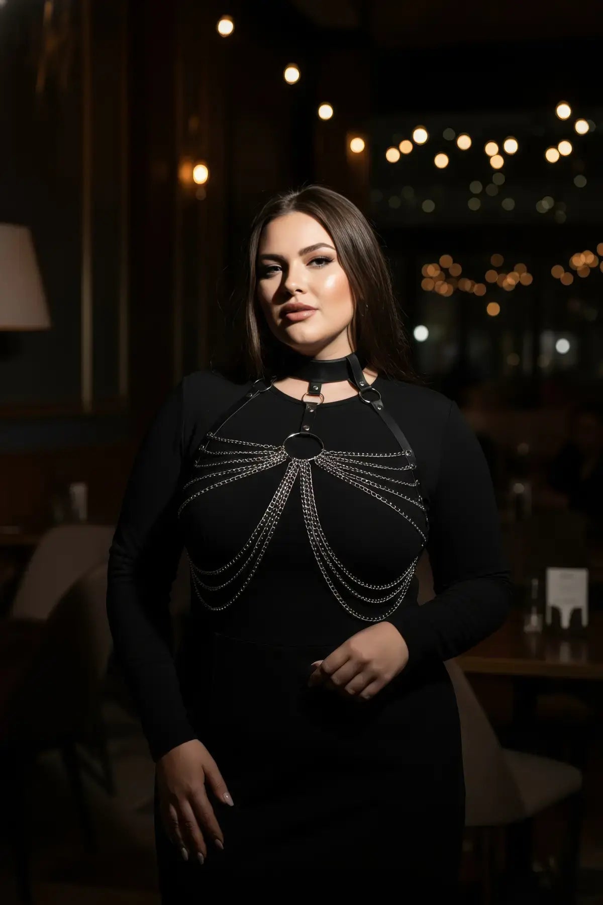 Plus-size black choker chain bib harness worn by model, vegan leather with metal chains across chest.