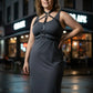 Plus size black vegan-leather collar chest harness with crossing straps worn over a gray dress.
