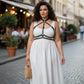 Plus-size black vegan leather collar chest harness with crossing straps worn over a white dress