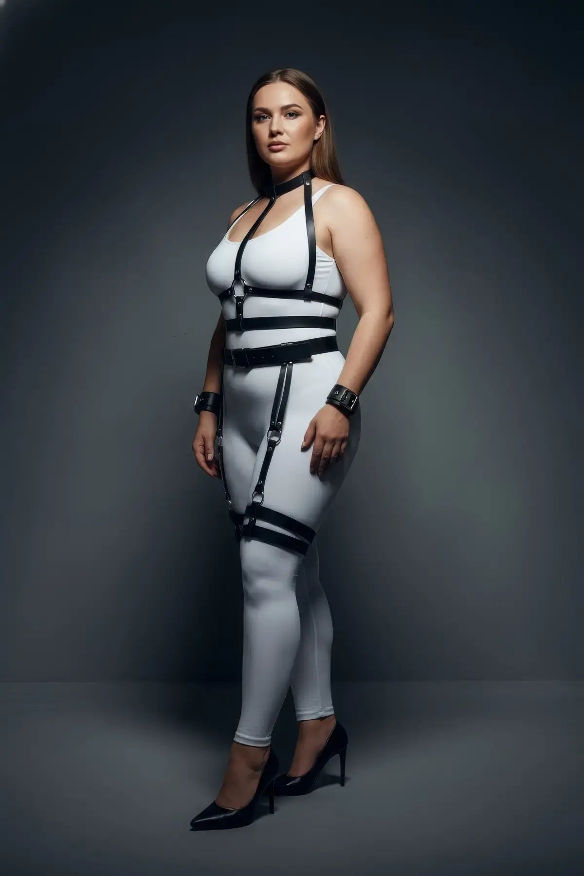 Plus-size black vegan-leather collar, cuffs, waist belt and garter full-body harness worn by model