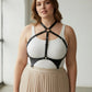Plus size black leather corset-style body harness worn over a white tank top