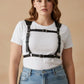 Plus size black leather corset-style body harness by HarnessClub, worn over a white T-shirt.