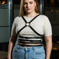 Plus-size black cross-strap leather body harness by HarnessClub worn over a white ribbed top.