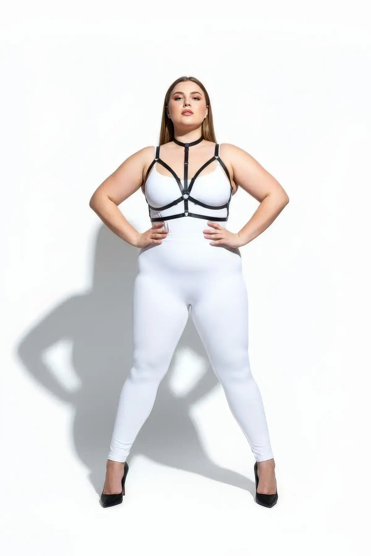 Plus-size black crossed-strap elastic harness with choker and waistband by HarnessClub on a white bodysuit.