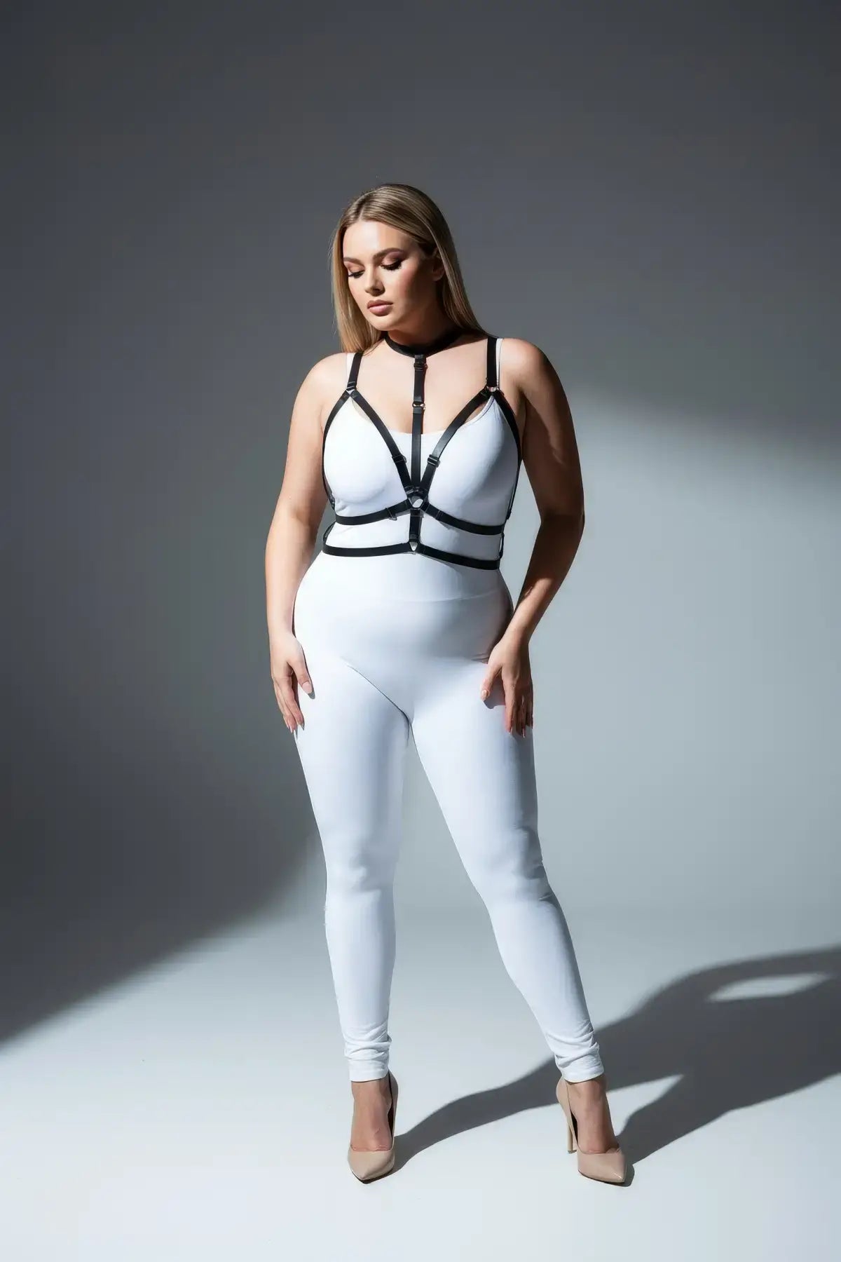 Plus-size black crossed-strap elastic harness with choker and waistband, worn over a white bodysuit.