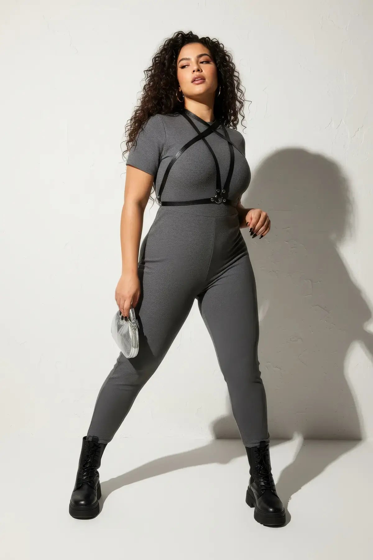 Plus size black crossing-strap cage harness worn over a gray fitted outfit; vegan leather accessory