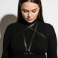 Plus-size black vegan-leather crossing-strap cage harness worn over a ribbed black turtleneck