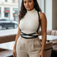 Plus-size black vegan-leather diagonal cross-strap body harness worn over a white turtleneck