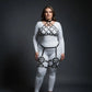 Plus-size black diamond lattice cage harness set over a white bodysuit; vegan leather straps.