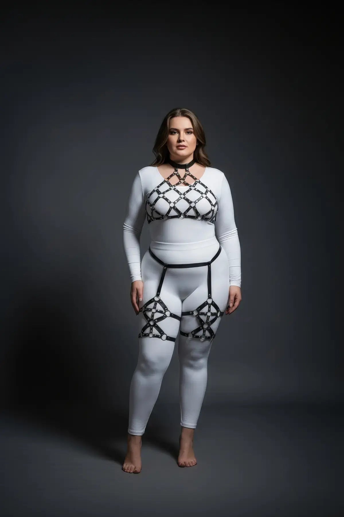 Plus-size black diamond lattice cage harness set over a white bodysuit; vegan leather straps.