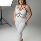 Plus size black elastic collar and O-ring harness with neck-to-waist straps worn over white bodysuit