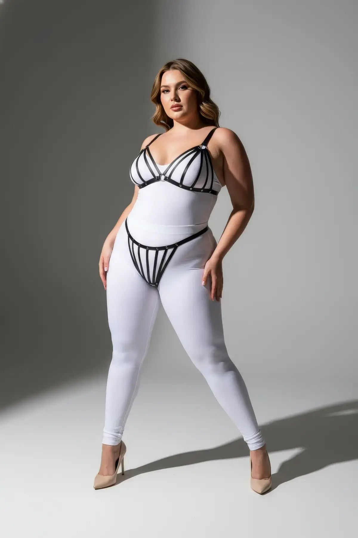 Plus-size black elastic multi-strap fantasy harness by HarnessClub, worn over a white bodysuit
