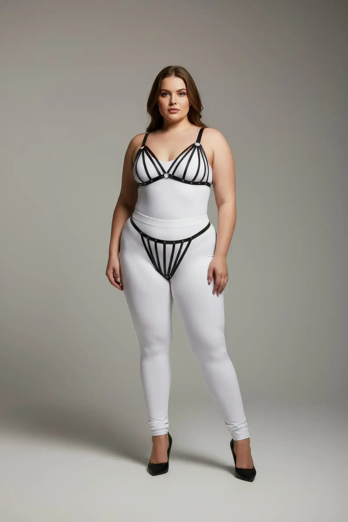 Plus-size black elastic multi-strap fantasy harness by HarnessClub worn over a white bodysuit