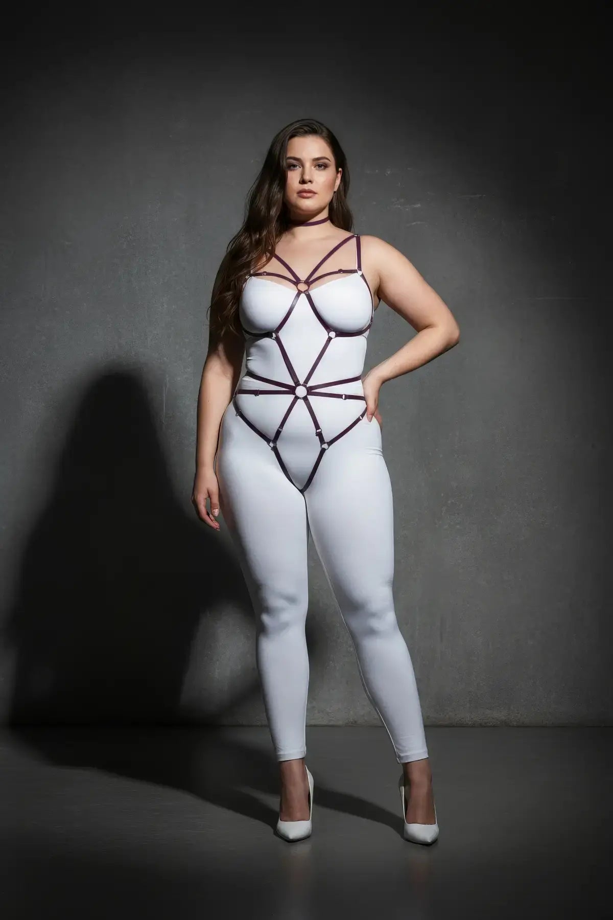 Plus-size black elastic O-ring web body harness worn over a white bodysuit on a model