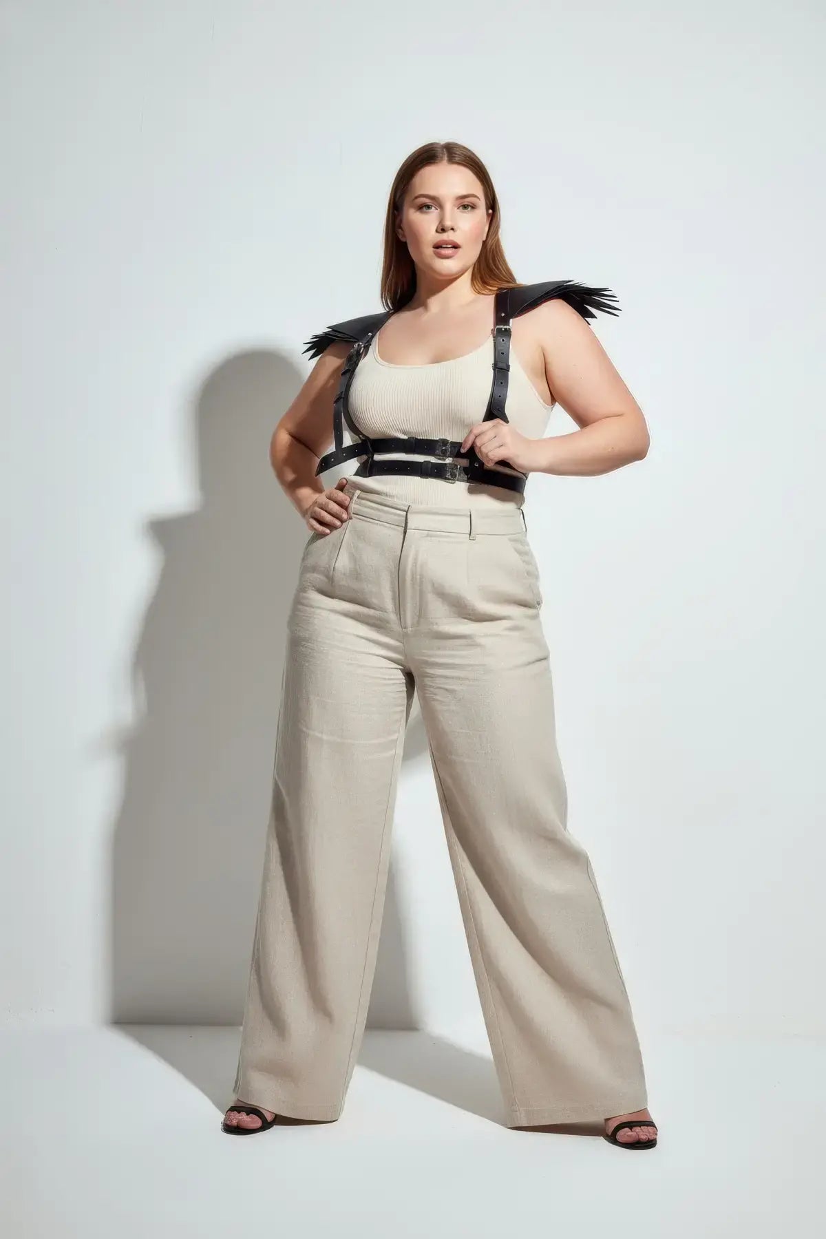 Plus-size black epaulette fringe shoulder harness in vegan leather by HarnessClub worn over beige ribbed tank