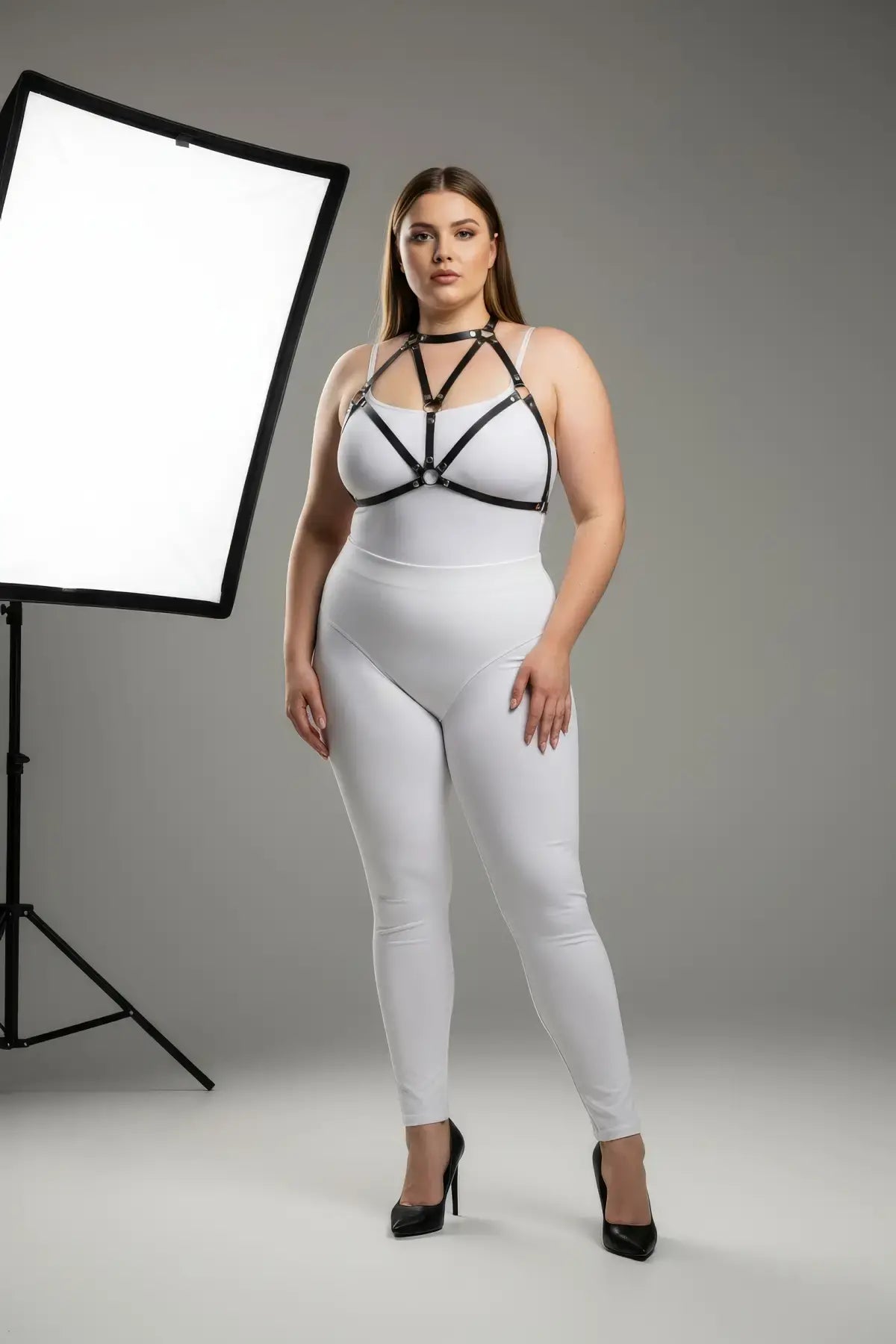 Plus Size Black Faux Leather Chest Harness by HarnessClub worn over a white bodysuit