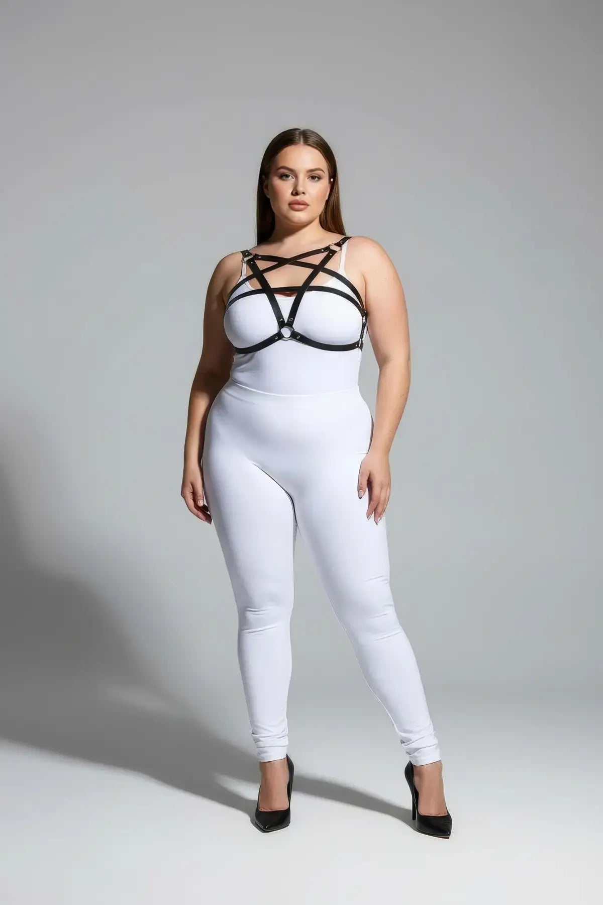 Plus size black faux leather chest harness set by HarnessClub on a model wearing a white bodysuit.