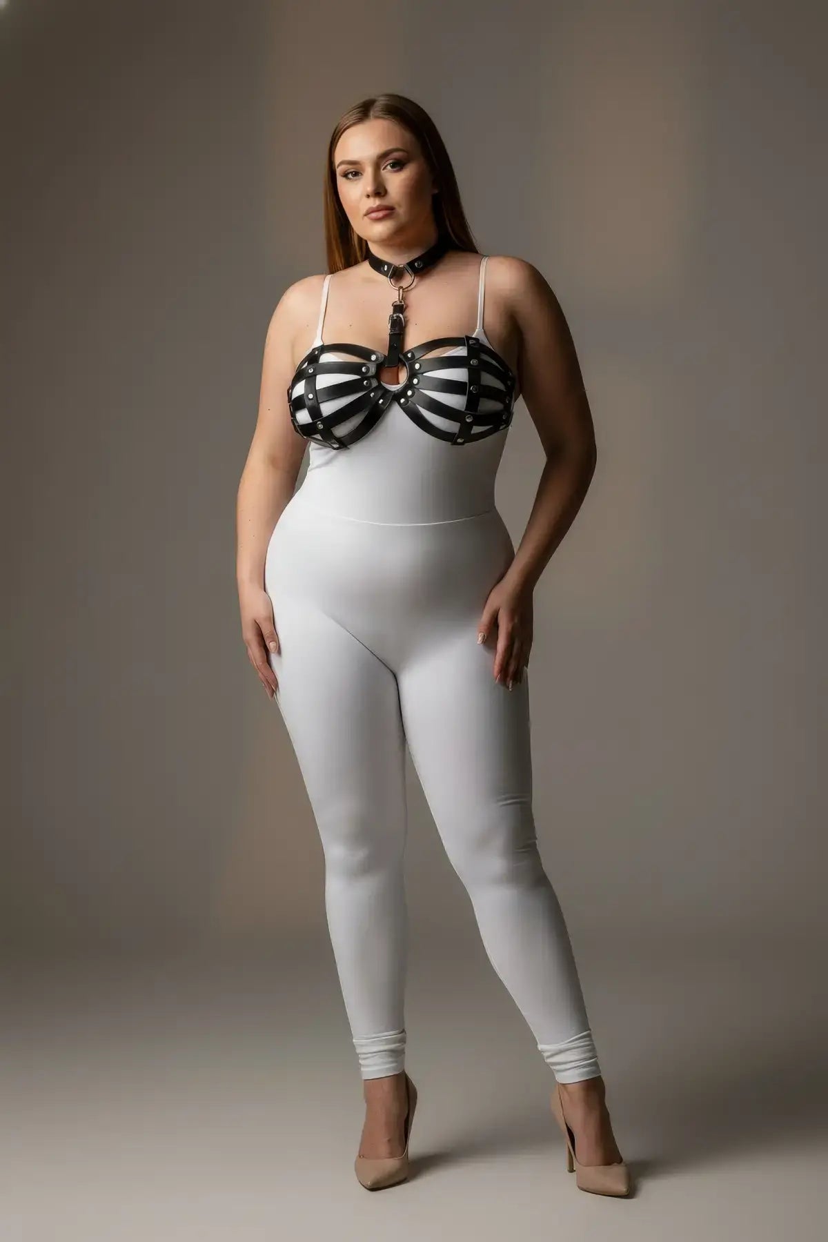 Plus Size Black Faux Leather Harness Set by HarnessClub; strappy riveted chest harness worn over a white bodysuit