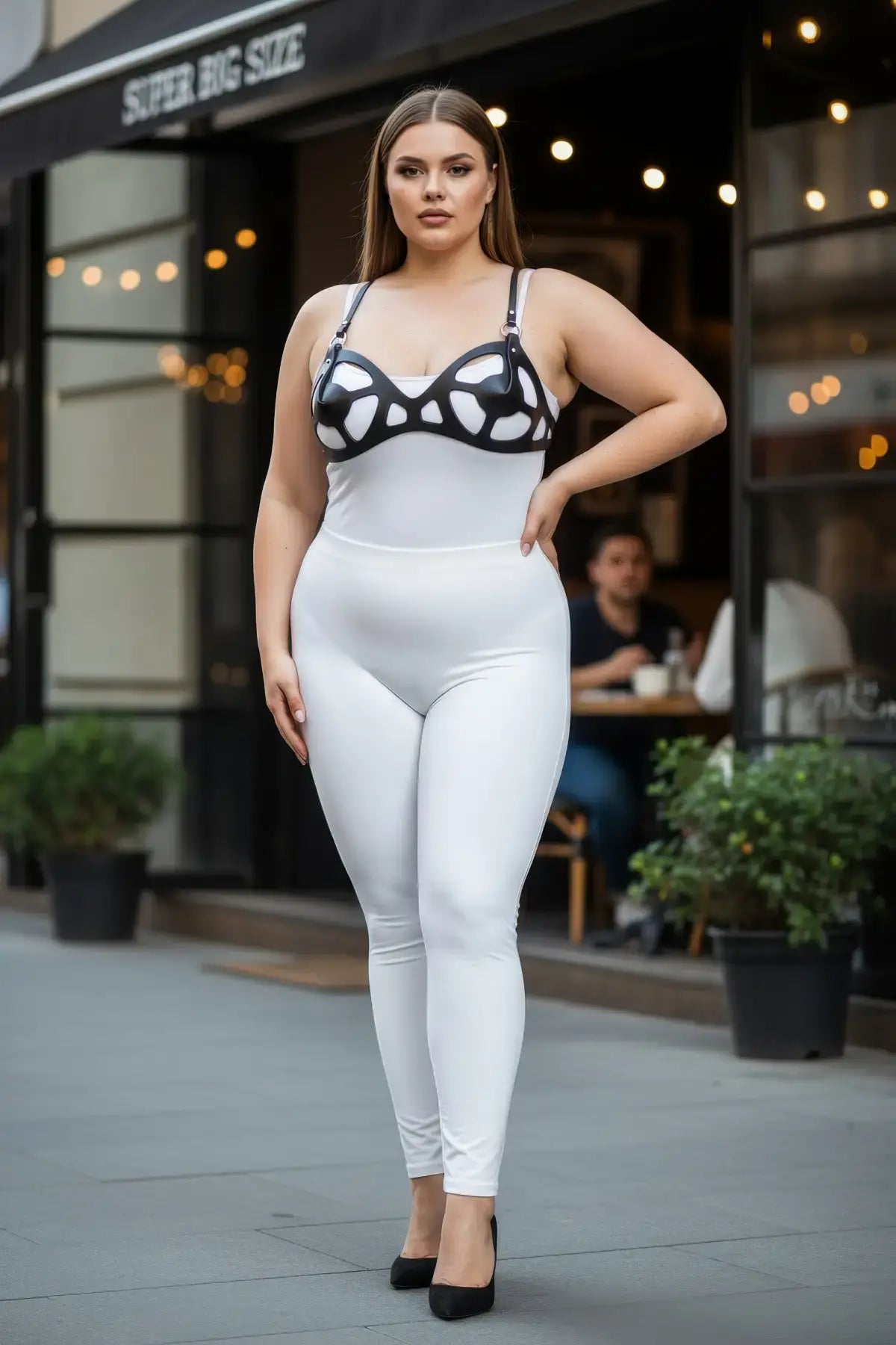 Plus-size black faux-leather fantasy body harness set over white bodysuit, model outdoors