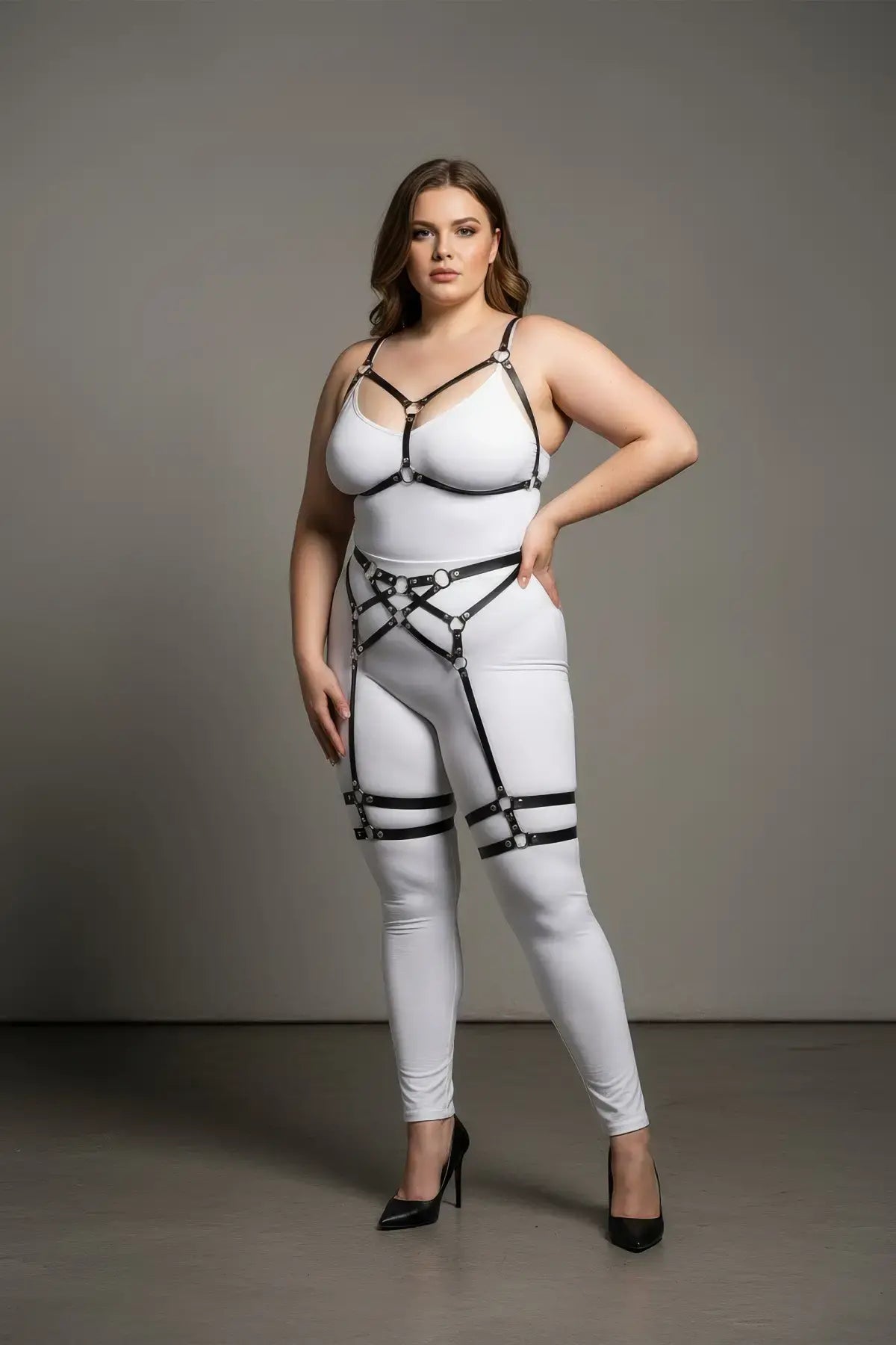 Plus-size black faux-leather harness set with garter straps worn over a white bodysuit.