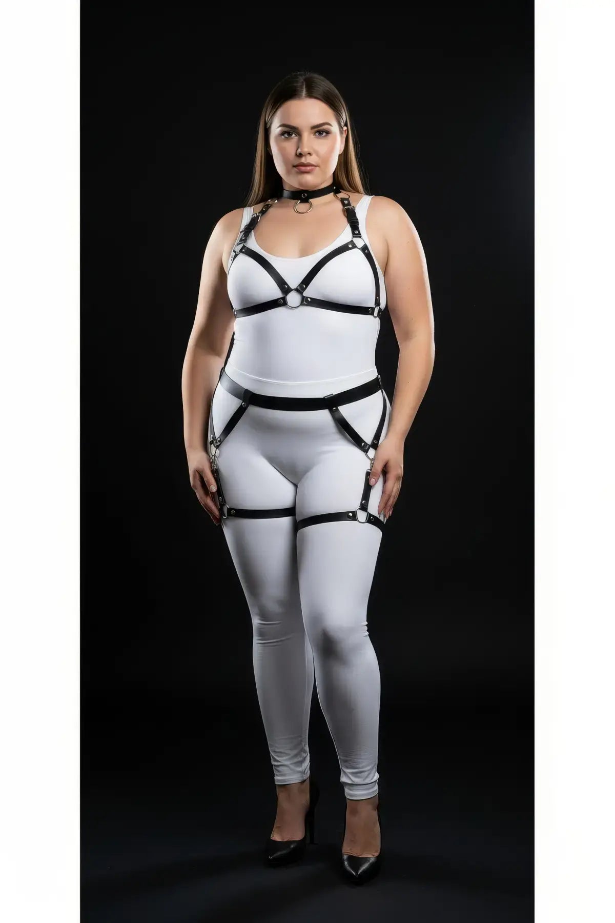 Plus-size black garter-frame full-body harness worn over a white bodysuit; vegan leather straps with metal rings.